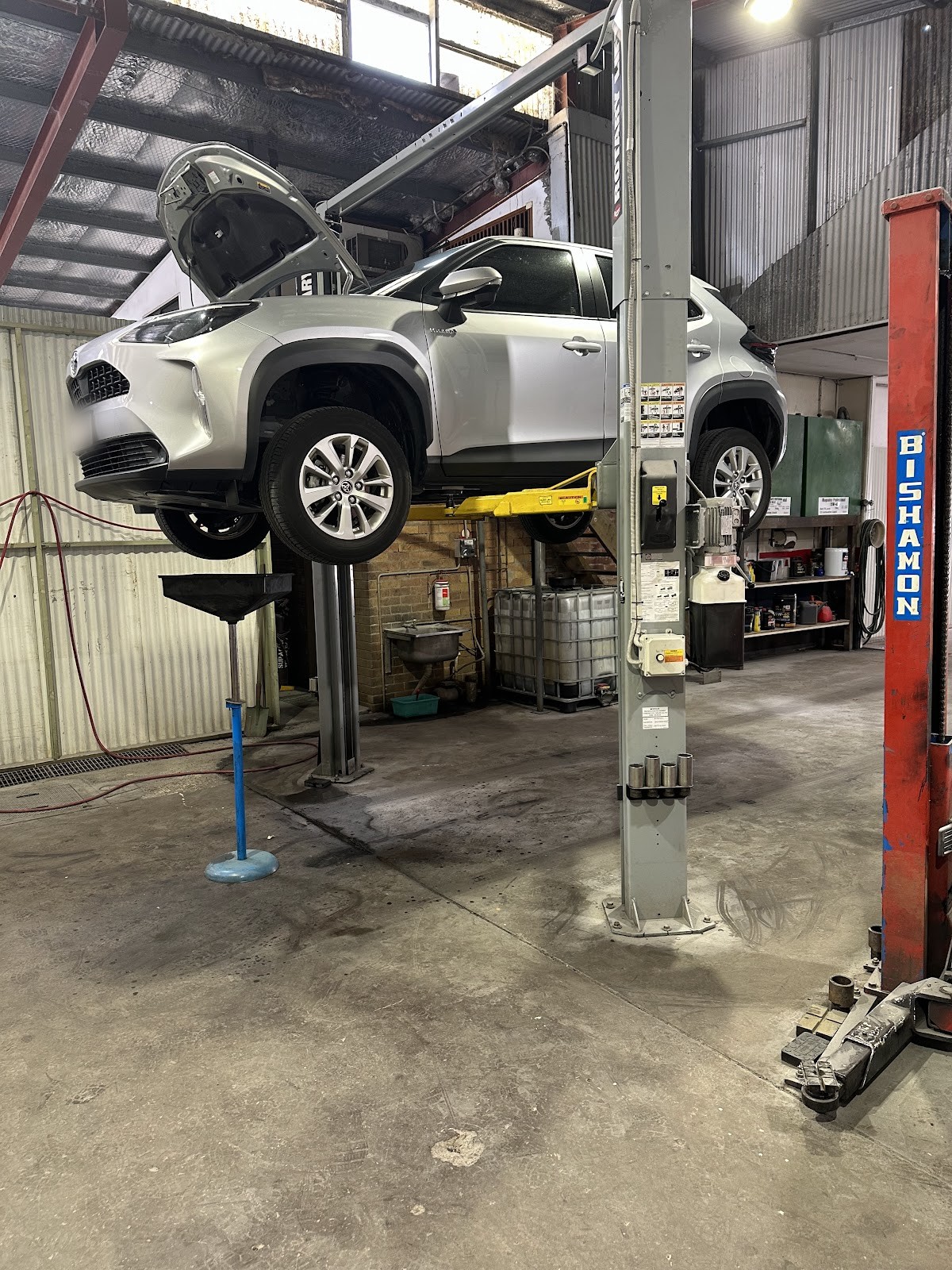 Silver Toyota SUV raised on a two post hoist for work underneath