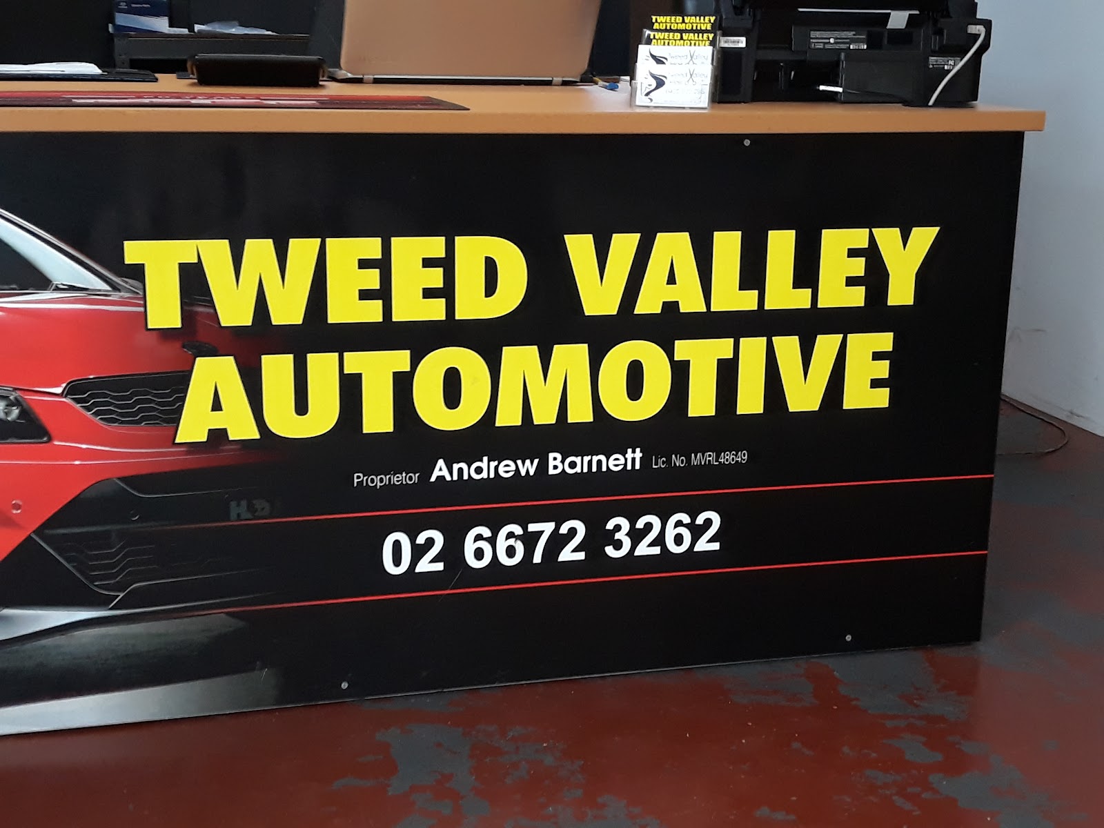 The reception counter sign reading Tweed Valley Automotive, Proprietor Andrew Barnett, licence MVRL48649
